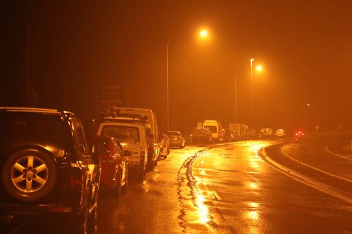 Les voitures font la queue sur le bord de la route près du centre de service de Taree, en attendant la réouverture de l'autoroute après avoir été inondée par les eaux de crue