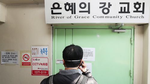 A man takes a photograph at the gate to the temporarily closed River of Grace Community Church, which will be shut until March 22.