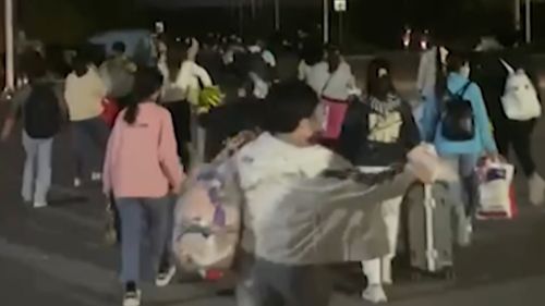  In this photo taken from video footage and released by Hangpai Xingyang, people with suitcases and bags are seen leaving from a Foxconn compound in Zhengzhou in central China's Henan Province in October 2022.
