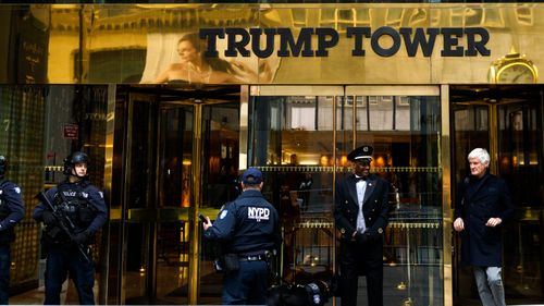 A doorman talks with security personnel at the front entrance of Trump Tower in New York.