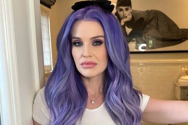 Kelly Osbourne poses with bright purple hair in her bathroom.