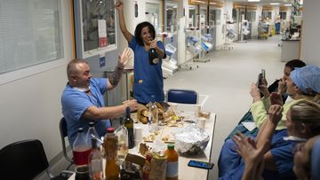 Nurse Bess Tribout, center, pops champagne to celebrate the new year in the COVID-19 intensive care unit at the la Timone hospital in Marseille, southern France, Saturday, Jan. 1, 2022. 