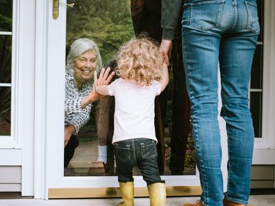 Grandmother greets grandchildren through glass