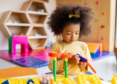 Beautiful African American girl playing with building blocks at the school