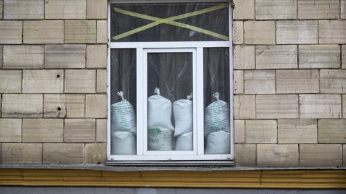 Une fenêtre est protégée avec du ruban adhésif et des sacs de sable contre les explosions à Kiev, en Ukraine. 