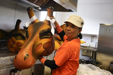 Artist Clary Salandy holds a giraffe head as she speaks with the Associated Press in her studio, ahead of the Platinum Jubilee Pageant, in London, Wednesday, June 1, 2022. 