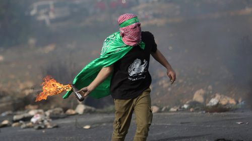 A Palestinian protester throws a molotov cocktail at Israeli soldiers. (AAP)