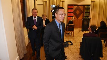 Victoria and Tasmania Consul-General of China Long Zhou (centre) departs a press conference at the Commonwealth Parliamentary Offices in Melbourne.