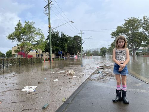 Ella Buckland's daughter stands on a flooded street in Lismore.
