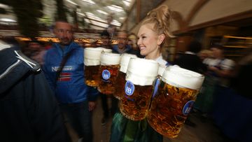A waitress carries some Mass (= one liter glass) of beer in the Hofbrauhaus tent on the opening day of the 2022 Oktoberfest beer fest.