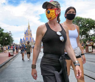Guests wear masks, as required, to attend the official re-opening day of the Magic Kingdom at Walt Disney World in Lake Buena Vista, Florida, on Saturday, July 11, 2020. Disney opened two Florida parks, the Magic Kingdom and Animal Kingdom, Saturday with limited capacity and safety protocols in place in response to the Coronavirus pandemic. 