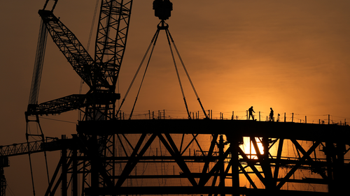 Workers are silhouetted as the sun sets over a construction site in Beijing, China, Saturday, Nov. 27, 2021.