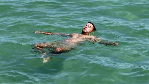 A man keeps cool in the water at Glenelg beach during yesterday's scorcher in Adelaide.