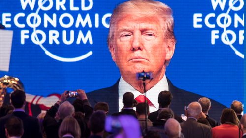 Participants watch US President Trump on a screen during the 48th Annual Meeting of the World Economic Forum. (AAP)