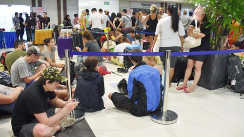  Tourists make a line at a ticket counter at Bali airport. (Image: AAP)