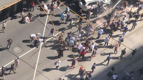 Commuters and shoppers are left shocked as more than 15 people are seen laying injured on the ground. (9NEWS)