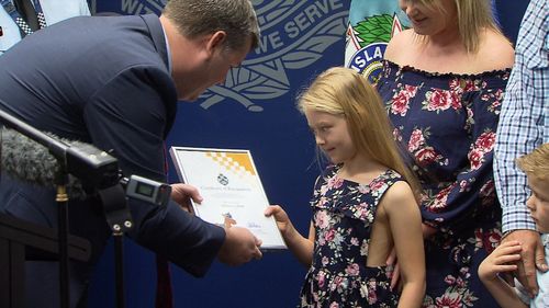 Addison is presented with a Certificate of Appreciation, a koala cop and a junior police cap she'll have to grow into. Picture: 9NEWS