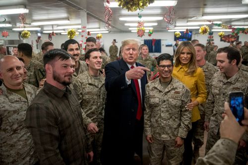 President Donald Trump and first lady Melania Trump pose for a photograph as they visit members of the military at a dining hall at Al Asad Air Base, Iraq.