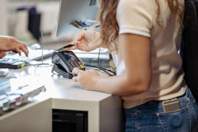 A  shot of a Middle Eastern female student buying some equipment in a store on campus.