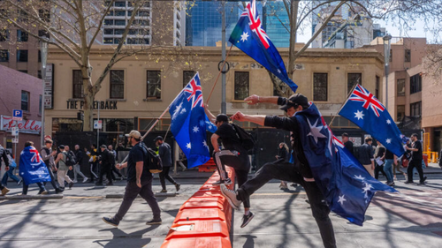 Anti-Government protesters leap of a road block as they march on September 13, 2025 in Melbourne, Australia. Australians rallied in multiple cities on the weekend in a call for unity after right-wing protesters staged marches through Australian CBDs last week