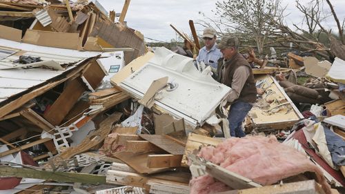 Roman Brown, left and Sam Crawford, right move part of a shower wall out of their way as they help a friend look for their medicine in their destroyed home outside of Hamilton, Mississippi.