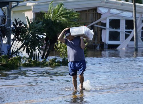Tom Nugen przenosi swoje rzeczy ze swojego zalanego domu po tym, jak huragan Ian przeszedł przez ten obszar w czwartek, 29 września 2022 r. W Fort Myers na Florydzie.