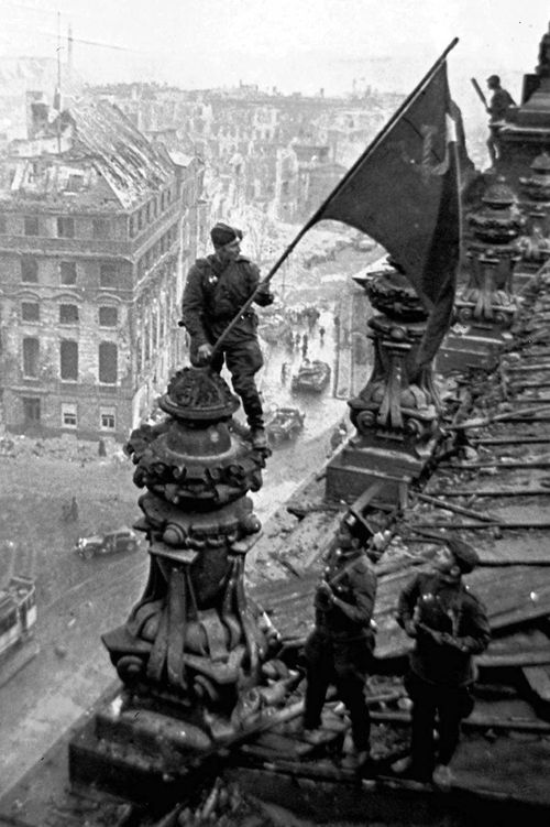 Soviet soldiers heist the red flag over the ruins of the Reichstag in Berlin in 1945. (AAP)