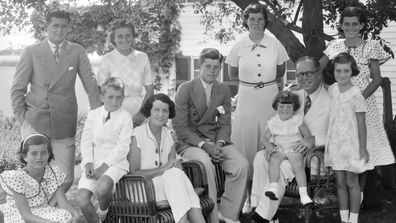 Un portrait de la famille Kennedy alors qu'ils sont assis à l'ombre de quelques arbres, Hyannis, Massachussetts, 1930.  Assis de gauche à droite sont : Patricia Kennedy (1926 - 2006), Robert Kennedy (1925 - 1968), Rose Kennedy (1890 - 1995), John F Kennedy (1917 - 1963), Joseph P Kennedy Sr (1888 - 1969) avec Edward Kennedy sur son genoux;  debout à partir de la gauche sont : Joseph P Kennedy Jr (1915 - 1944), Kathleen Kennedy (1920 - 1948), Rosemary Kennedy (1918 - 2005), Eunice Kennedy (arrière, à pois) et Jean Kennedy.  (Photo b