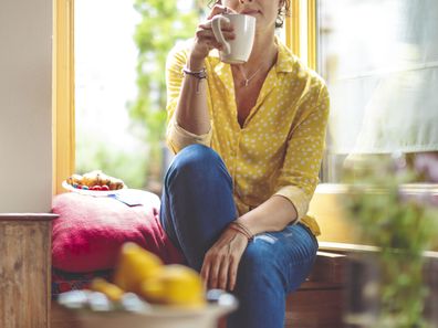 Woman drinking tea at home alone