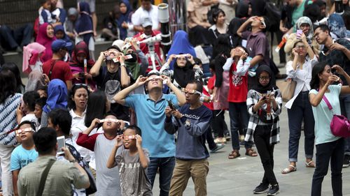 Stargazers look up at the sun with protective glasses to watch the solar eclipse from Jakarta, Indonesia.