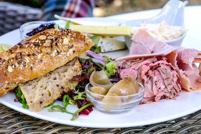 Ploughmans Lunch on a White Plate with Ham, cheese, coleslaw, pickles and a Bread Roll