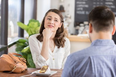 Young woman makes a disinterested face while on a date in a coffee shop. 