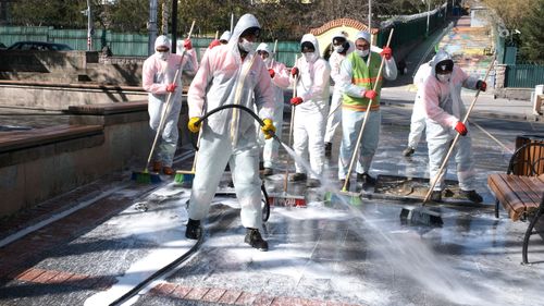 Municipality workers wearing face masks and protective suits disinfect Kugulu public garden amid the coronavirus outbreak, in Ankara, Turkey