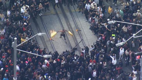 A man with batons lit on fire at the rally in Sydney.