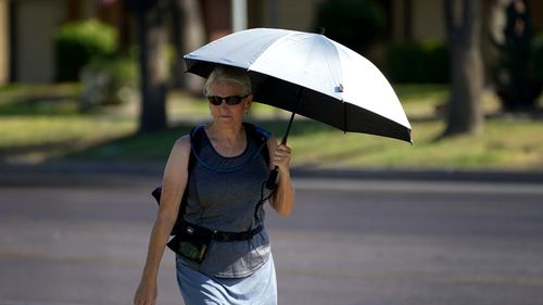 A lady uses an umbrella for shade to combat high temperatures, in Phoenix, Arizona.