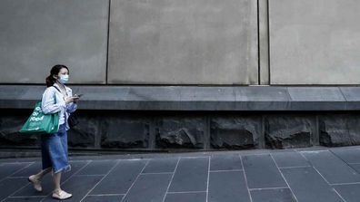 A woman in a face-mask walks down the street in Melbourne.