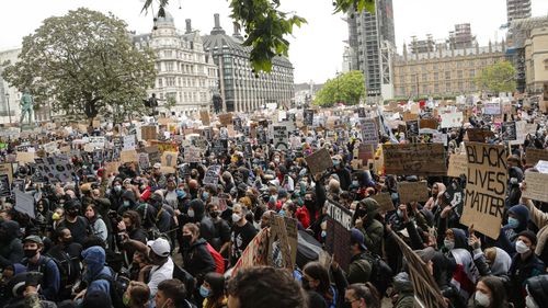 People hold placards during a Black Lives Matter rally in Parliament Square in London, Saturday, June 6, 2020