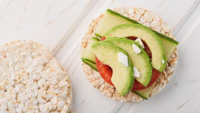 Top view vegan breakfast rice cake / rice cracker with avocado and tomato.