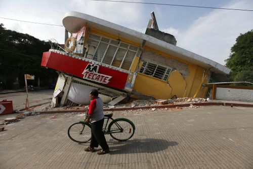 A man walks his bike past a building felled by a 7.1 earthquake, in Jojutla, Morelos state. (AP)