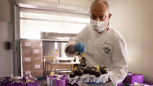 One of Belgium's top chocolate producers Dominique Persoone, wearing a face mask to protect against coronavirus, displays one of his chocolate Easter eggs at his Chocolate Line warehouse in Bruges, Belgium, Friday, April 10, 2020