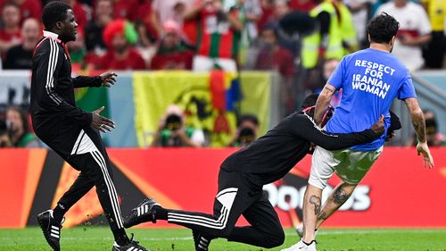 Security tackles a pitch invader during the Portugal-Uruguay match.