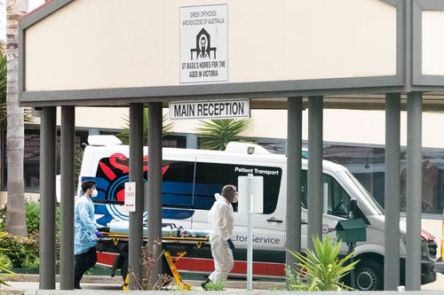 MELBOURNE, AUSTRALIA - 27 LUGLIO: Gli addetti al servizio di ambulanza spingono una barella nelle case di San Basilio per la struttura Aged a Fawkner il 27 luglio 2020 a Melbourne, Australia. Victoria ha registrato 532 nuovi casi di coronavirus e altri sei decessi. L'area metropolitana di Melbourne e la contea di Mitchell rimangono bloccate a causa dell'aumento dei casi di COVID-19 attraverso le trasmissioni comunitarie, con le persone autorizzate a uscire di casa solo per fare esercizio fisico, lavorare, acquistare beni essenziali o accedere all'assistenza all'infanzia e all'assistenza sanitaria.