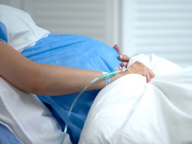 Pregnant woman lying in hospital bed.