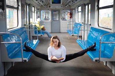 flexible female yogi reading book in the underground carriage sitting in gymnastic split. Concept of inspiration, harmony and health