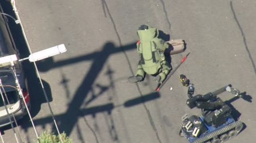 The officer and the robot are taking turns in examining the device. (9NEWS)