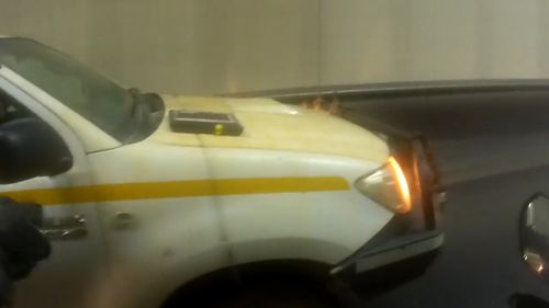 Motorbike rider passes laptop through car window while driving through Sydney tunnel.