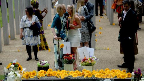 People comfort each other following a service at the July 7 memorial in Hyde Park, London. (AAP)