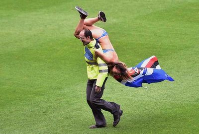 The guard sweeps the streaker off her feet. (Getty)