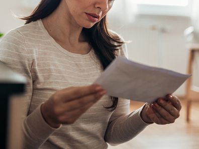 Worried woman reading a letter at home.