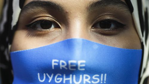 A woman wears a face mask reading 'Free Uyghurs' as she attends a protest during the visit of Chinese Foreign Minister Wang Yi in Berlin, Germany.